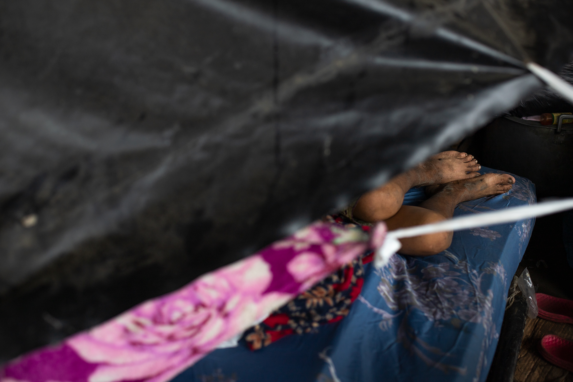 Una anciana damnificada descansa en un colchón dentro de un refugio construido con plásticos y trozos de madera en los bajos del puente frente al sector Chamelecón. San Pedro Sula, 21 de noviembre de 2020. Foto: Martín Cálix.