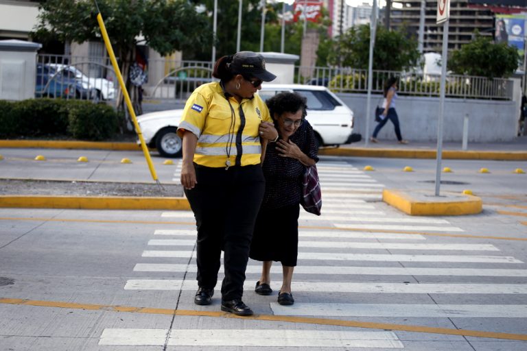 Jenny Aguirre ayuda a una anciana a cruzar una calle custodiada por agentes de orden vial