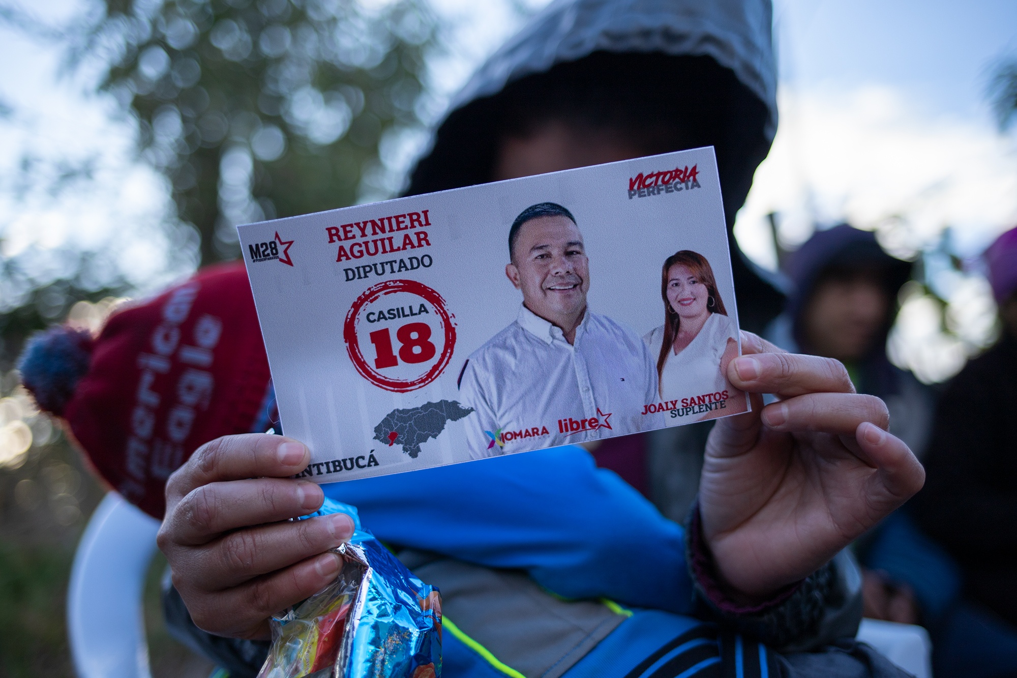 Una joven sostiene un sticker del precandidato a diputado, Reynieri Aguilar del movimiento M28 del Partido Libre. Yamaranguila, Intibucá, 19 de febrero de 2021. Foto: Martín Cálix.