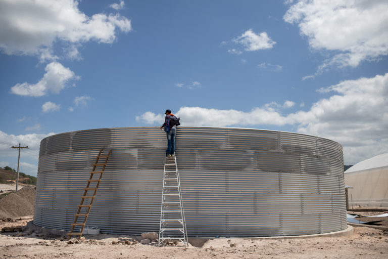 An Orchid ZEDE employee inspects the rainwater storage cisterns. San Marcos de Colon, July 23,  2021. Photo by Martín Calix.