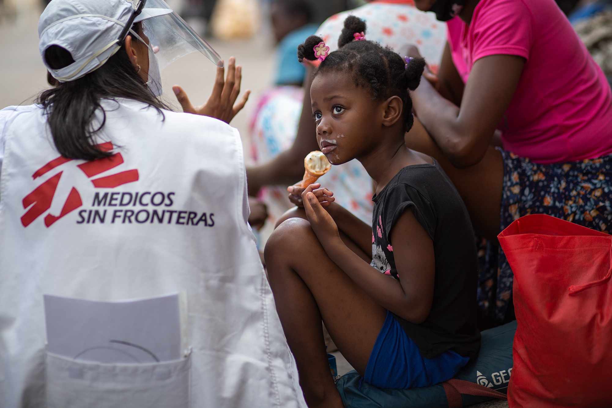 Una niña haitiana come un helado mientras su madre habla con el personal de Médicos Sin Fronteras. Comayagüela, 28 de octubre de 2021. Foto: Martín Cálix.