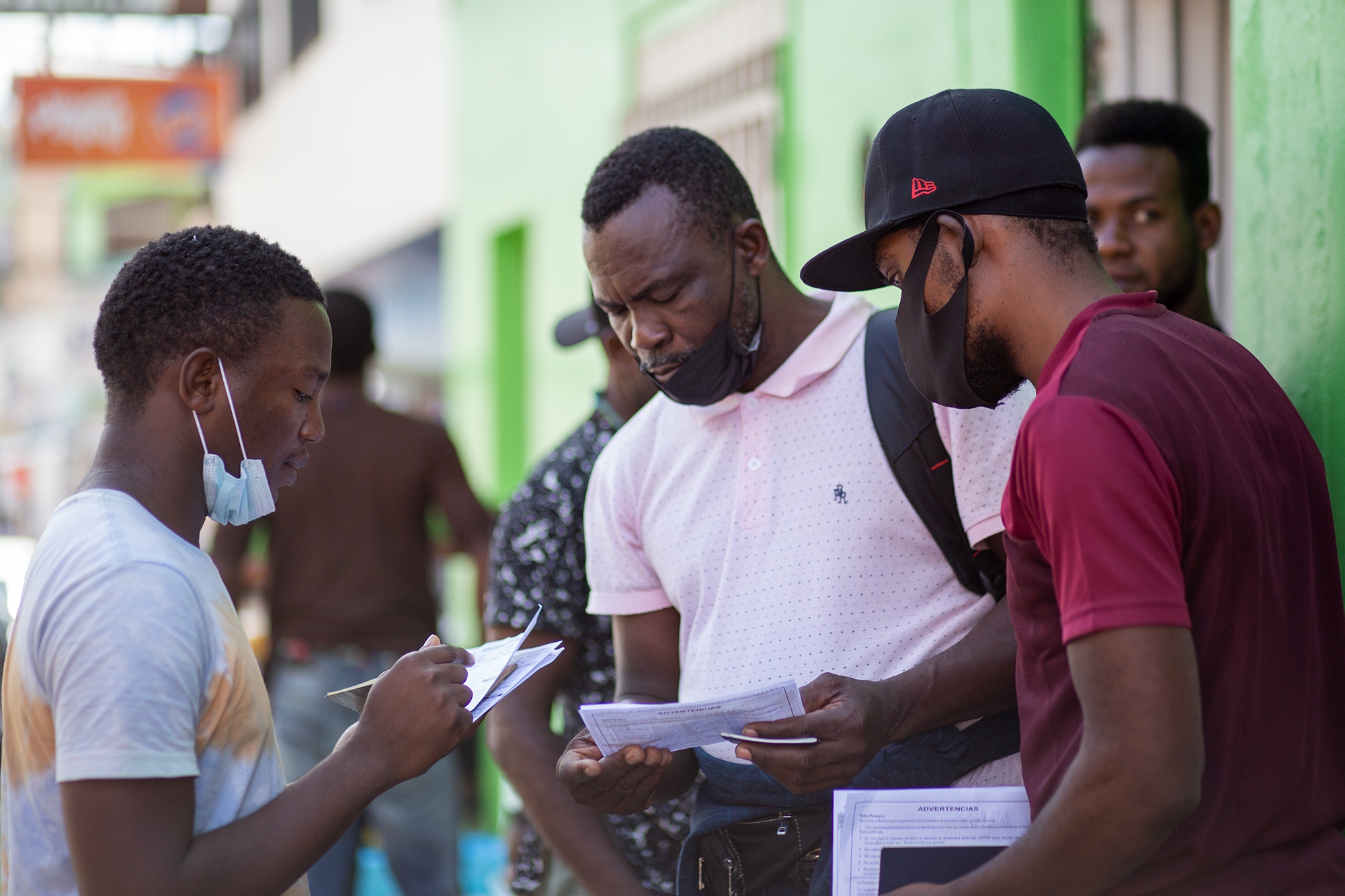 Tres migrantes haitianos revisan los tickets comprados en una empresa de transportes que les llevará desde la capital hondureña hasta la frontera de Agua Caliente. Comayagüela, 27 de octubre de 2021. Foto: Martín Cálix.