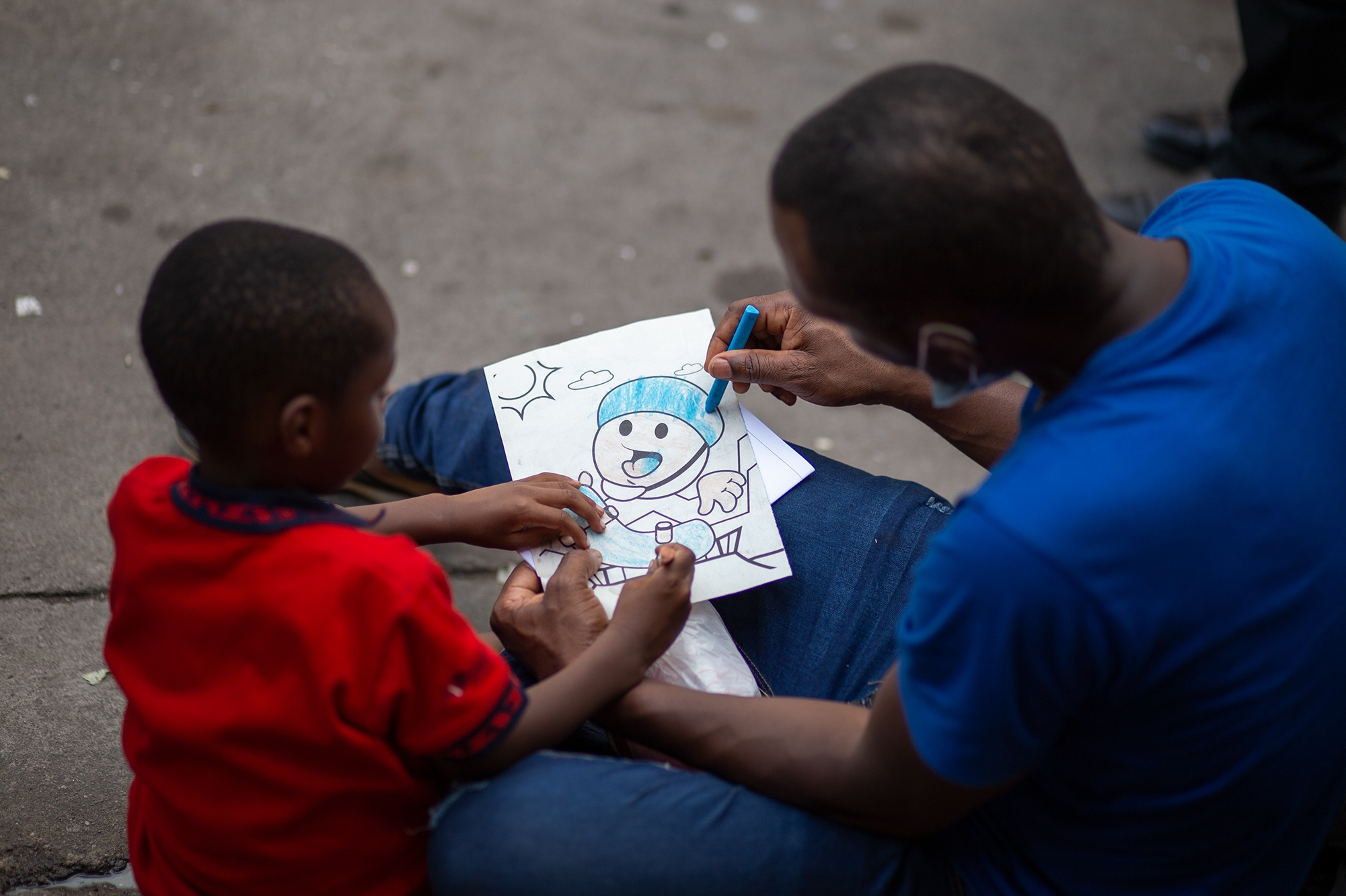 El haitiano Dor Kesmel de 40 años, pinta un dibujo junto a su hijo chileno Dor Seïde de 4 años. Comayaguela, 28 de octubre de 2021. Foto: Martín Cálix.