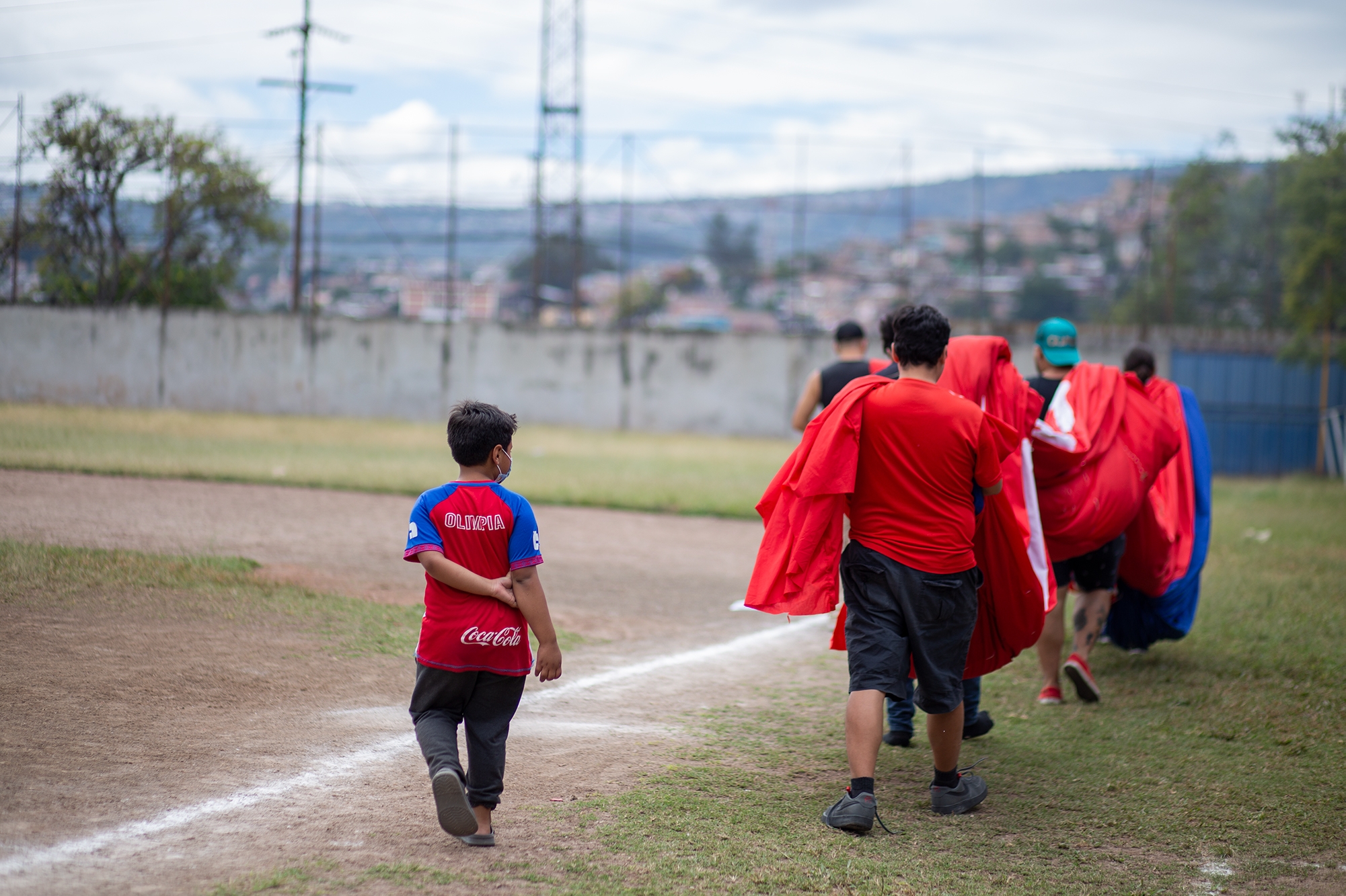 Un grupo de jóvenes de la barra Ultra Fiel cargan la manta hacia la cancha de pelota Lempira Reina para trabajar en ella. Tegucigalpa, 26 de noviembre de 2021. Foto: Martín Cálix.