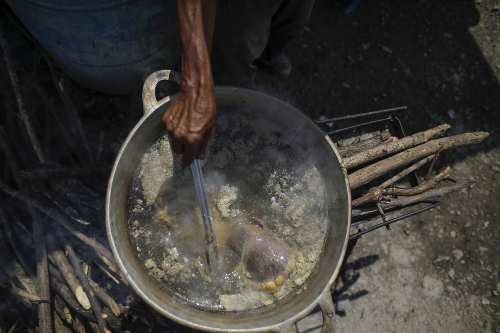 Un hombre prepara sus alimentos en la ciudad Mel Zelaya, una toma de tierras. Foto CC/Jorge Cabrera