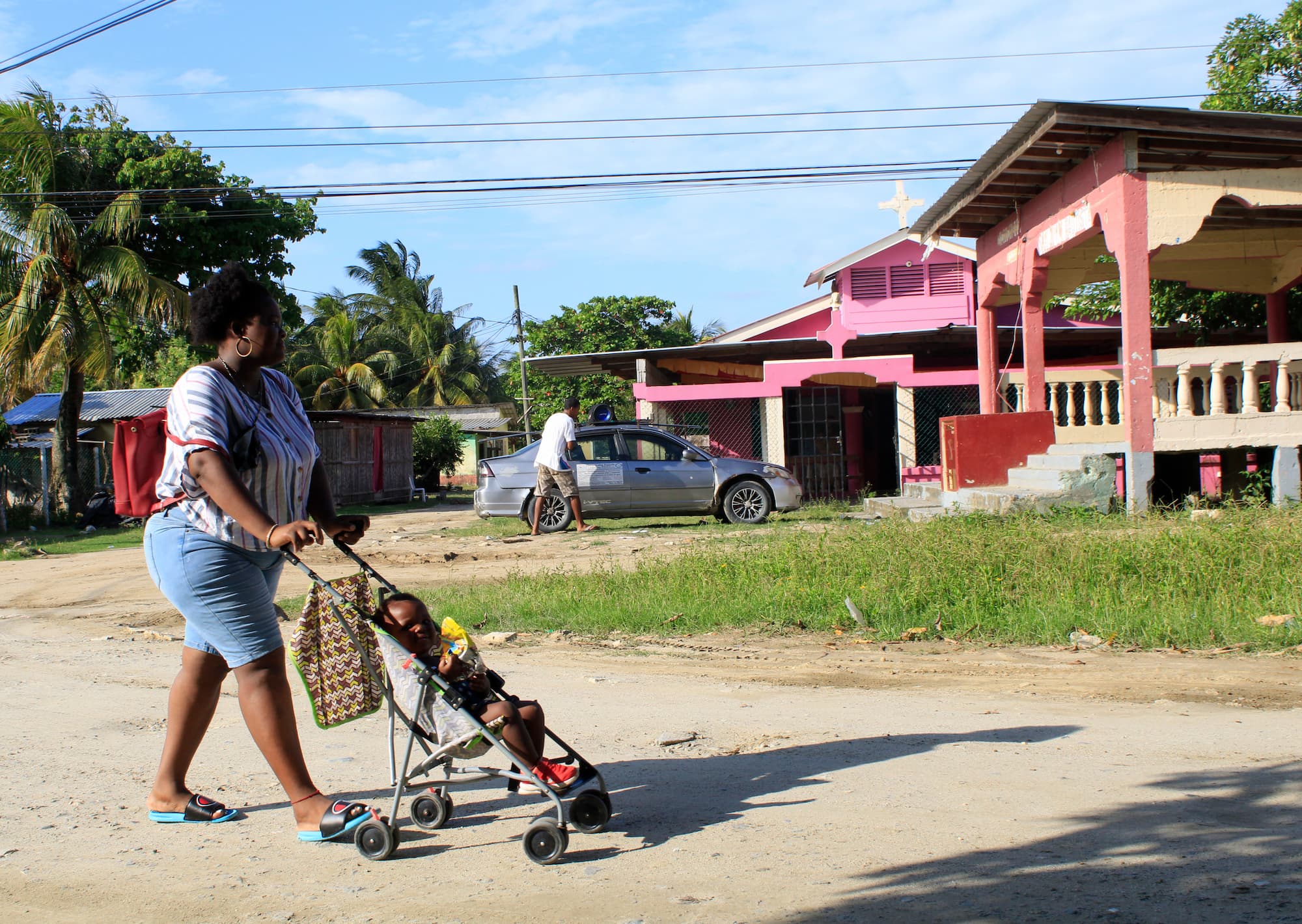 Una madre garífuna cruza la calle con su hijo dentro de un cochecito por el centro de la comunidad de San Juan ubicada en Tela, Atlántida. Foto CC/Amílcar Izaguirre