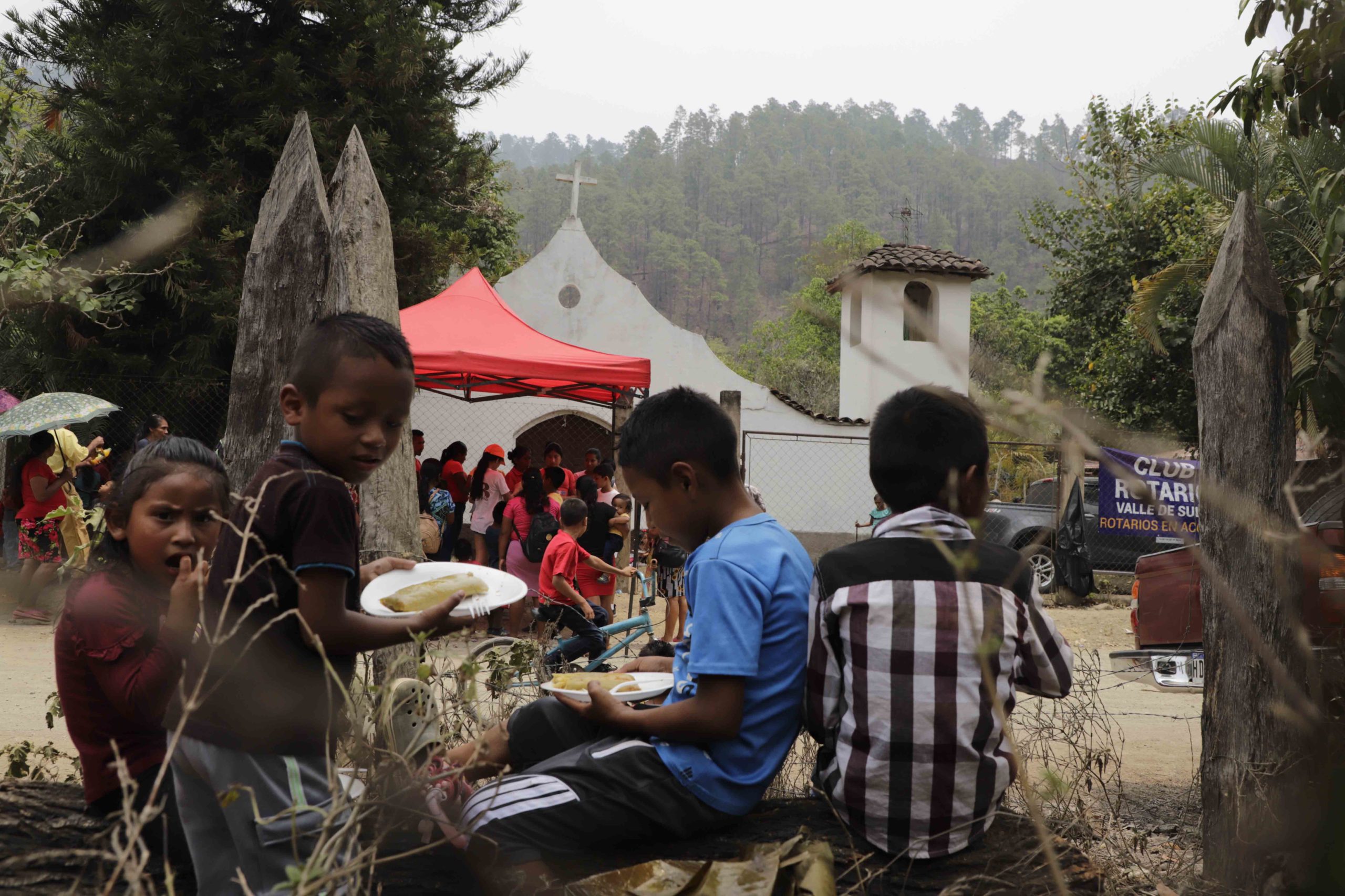 Sentados en un tronco seco, cuatro niños tolupanes comparten el almuerzo frente a la iglesia católica de Piedra Gorda, Locomapa. Los tolupanes se establecieron en las montañas de Yoro y Francisco Morazán. CC/Amilcar Izaguirre