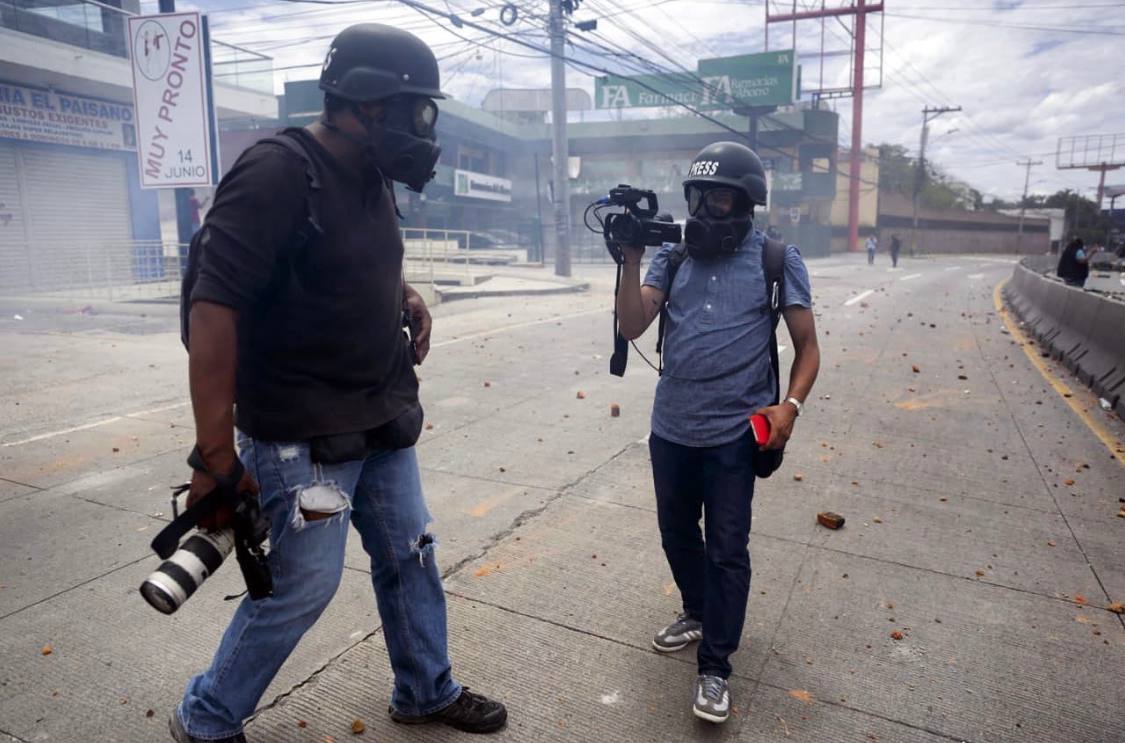 Miembros de la prensa se protegen de los gases lacrimógenos durante una protesta en Tegucigalpa 06 de agosto de 2019. Foto CC/Jorge Cabrera