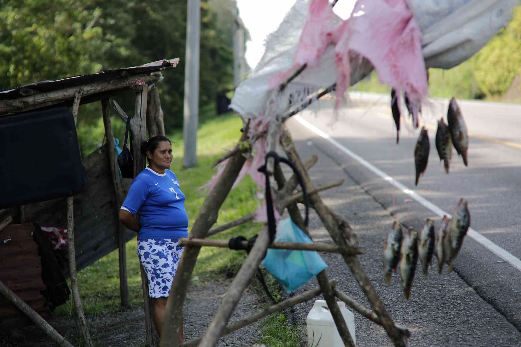 Rosa Idalia espera a un lado de la carretera para poder vender los pescados que sacan del Lago de Yojoa. Foto CC/ Jorge Cabrera.