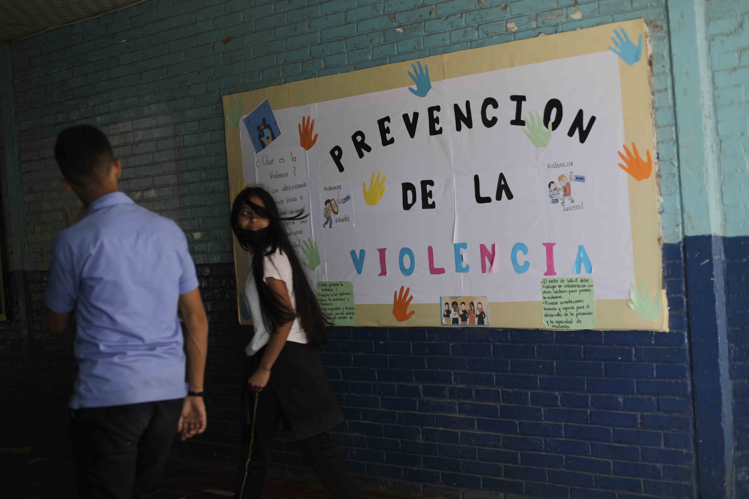 Estudiantes del centro estudiantil Milla Selva cruzan frente a un mural de prevención de la violencia. Foto CC/Jorge Cabrera