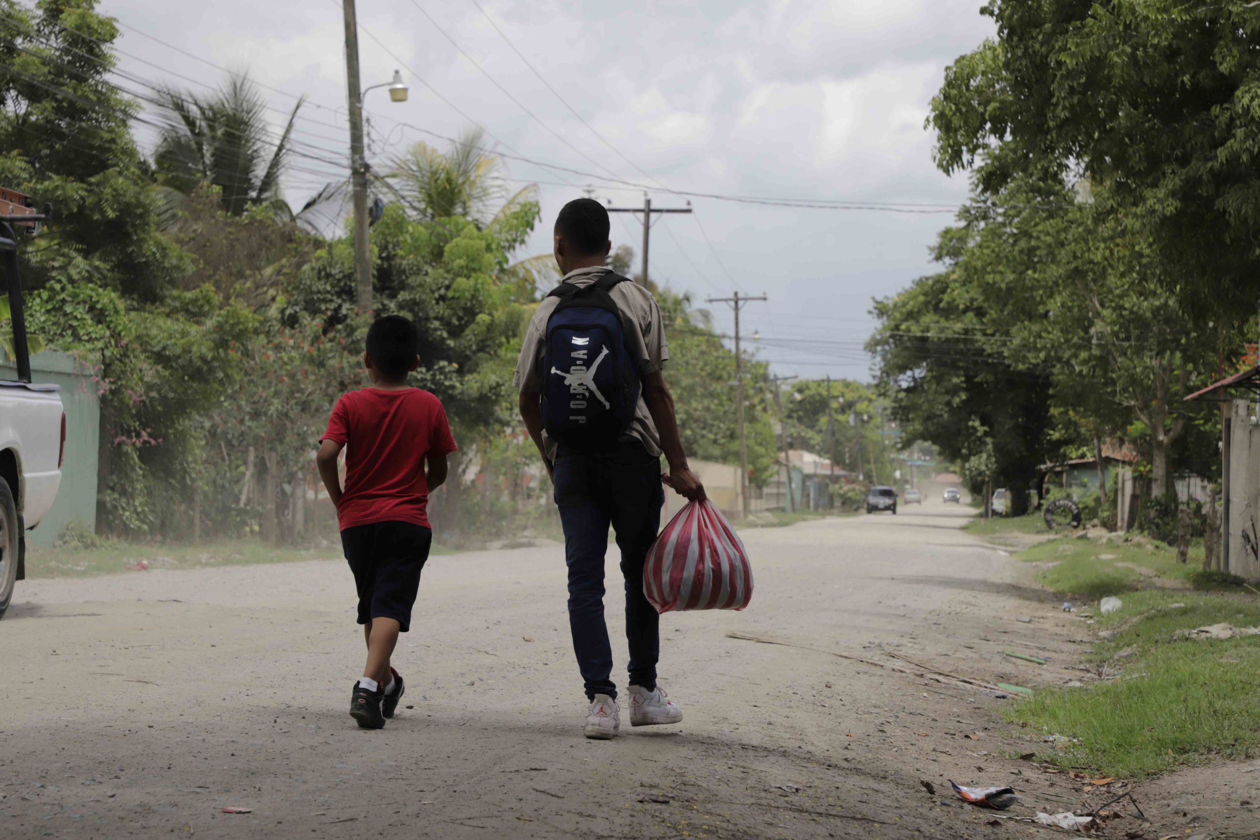 Un padre y su hijo caminan por la calle principal en la colonia Monterrey, ubicada en lo bajo de Choloma, algunos vecinos comentaron que en esta colonia la violencia no es un problema, pero sí les preocupa el desempleo. Foto CC/Amilcar Izaguirre