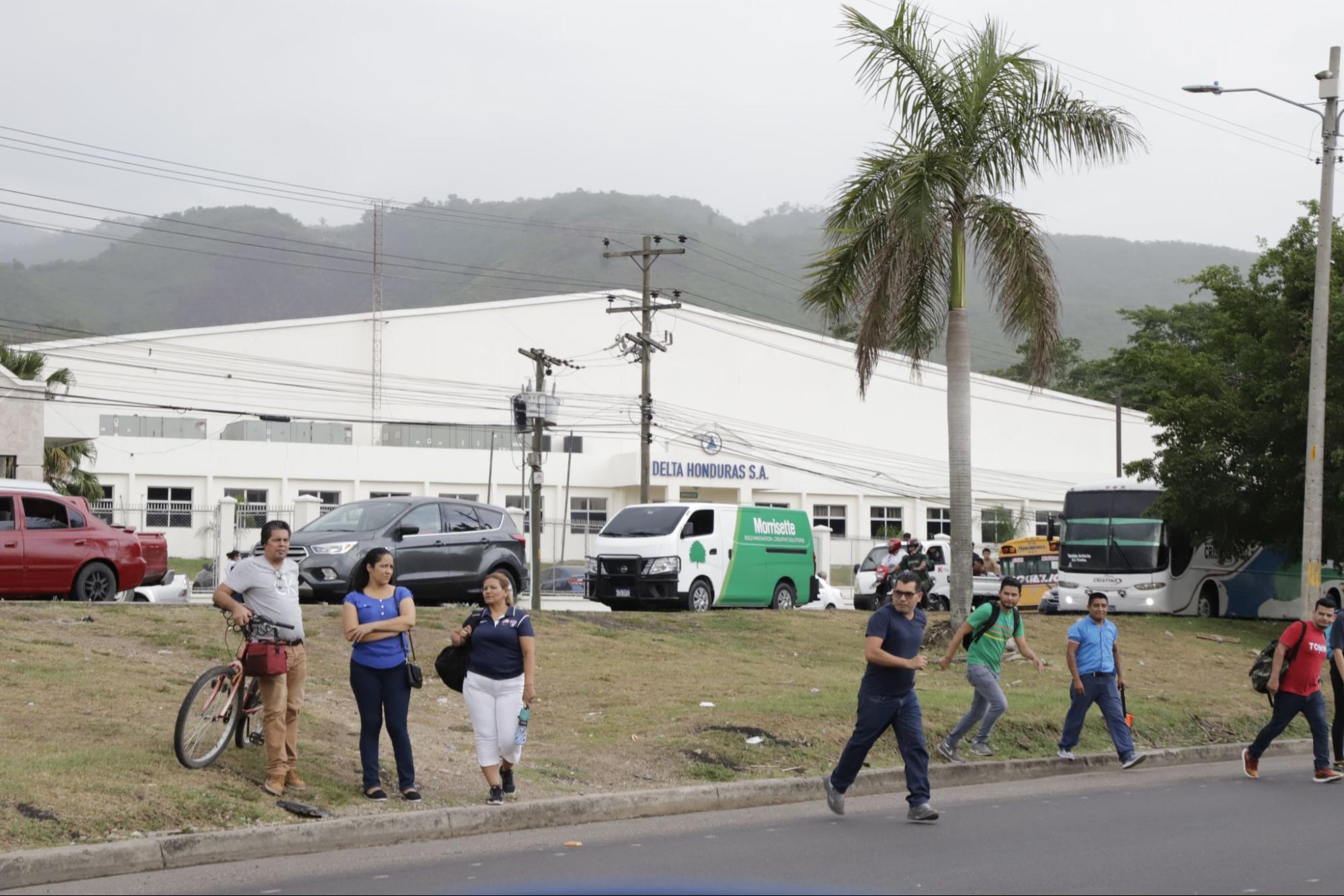 Empleados de Delta Aparrel cruzan la carretera para tomar los autobuses que los llevan de regreso a sus hogares. Fotos CC/Amílcar Izaguirre