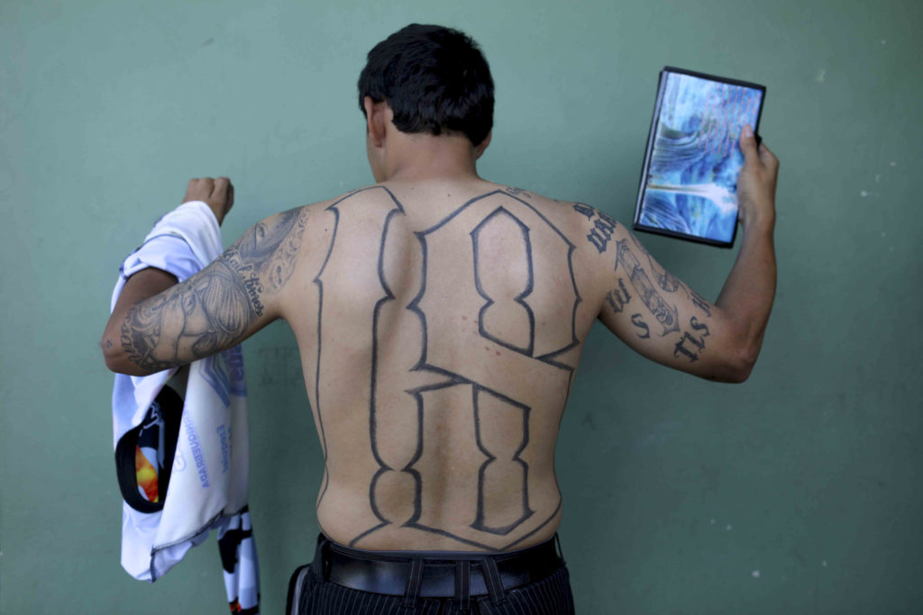 Elíseo posa mostrando los tatuajes del pasado mientras carga una Biblia que representa su nueva vida. Foto CC/Jorge Cabrera