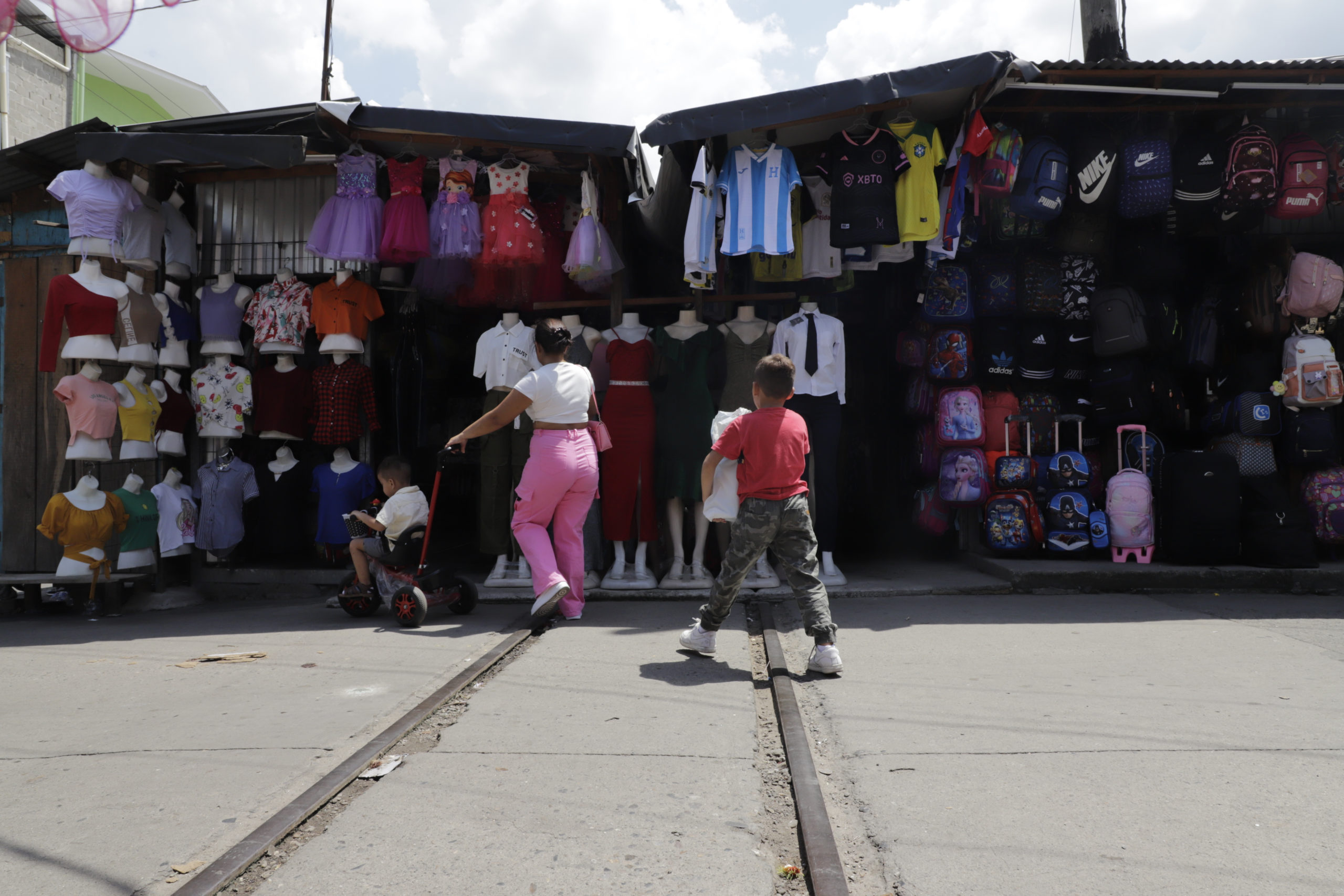 Una madre y sus dos hijos caminan entre la línea del tren en la cuarta calle y la primera avenida de San Pedro Sula, una de las zonas más nutridas de vendedores informales. Foto CC/Amilcar Izaguirre