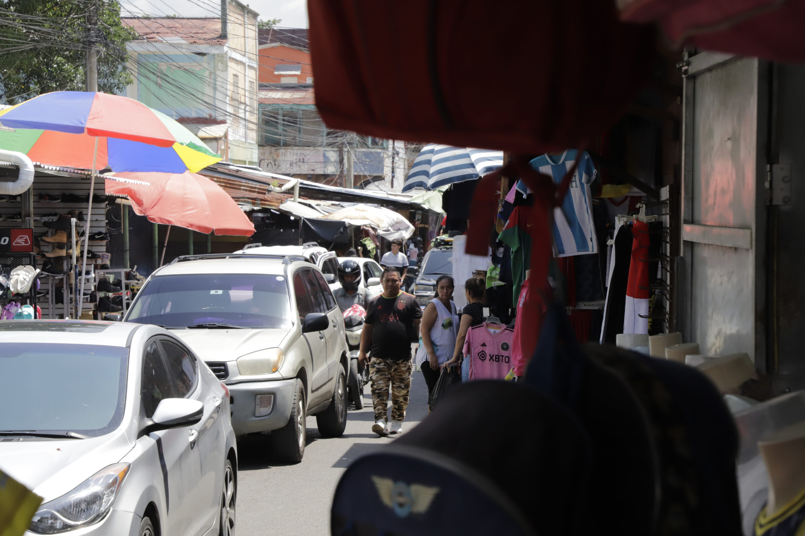 Vehículos y transeúntes circulan por la primera avenida del Centro de San Pedro Sula, los puestos de ventas de los vendedores informales apenas dejan un carril para que ambos puedan pasar. Foto CC/Amilcar Izaguirre