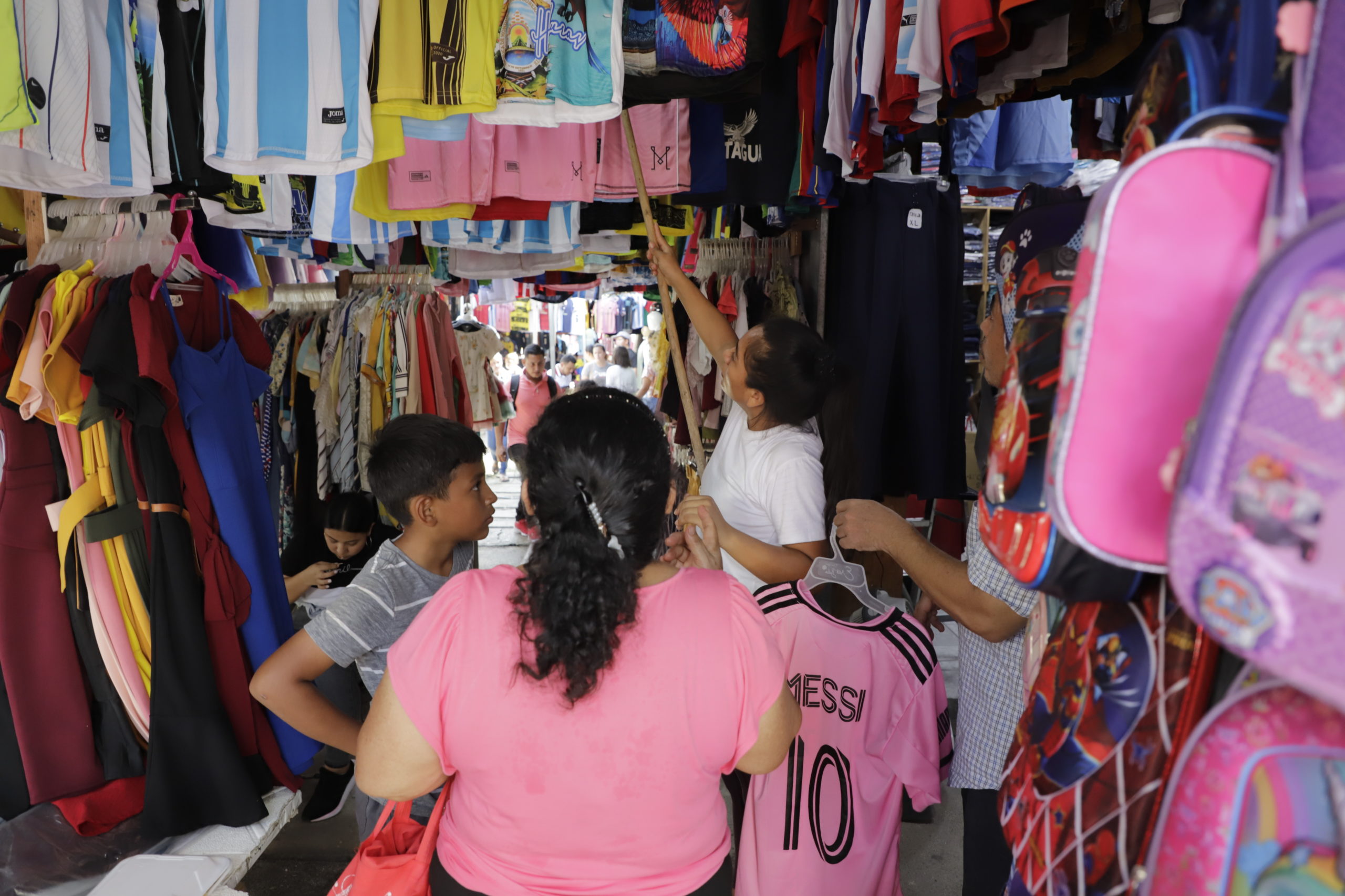Una madre con su hijo eligen entre  la ropa que cuelga de un puesto informal la réplica de la camiseta que usa Lionel Messi, en el Inter Miami de la liga MLS en Estados Unidos. Los vendedores aseguran que aquí los precios son más accesibles. Foto CC/Amilcar Izaguirre