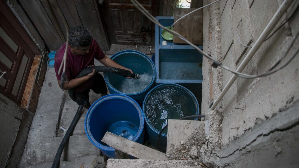 Un vecino llena los barriles de plástico con agua. El precio del barril de agua llega hasta los 150 lempiras. Tegucigalpa, abril de 2024. Foto CC/ Fernando Destephen.