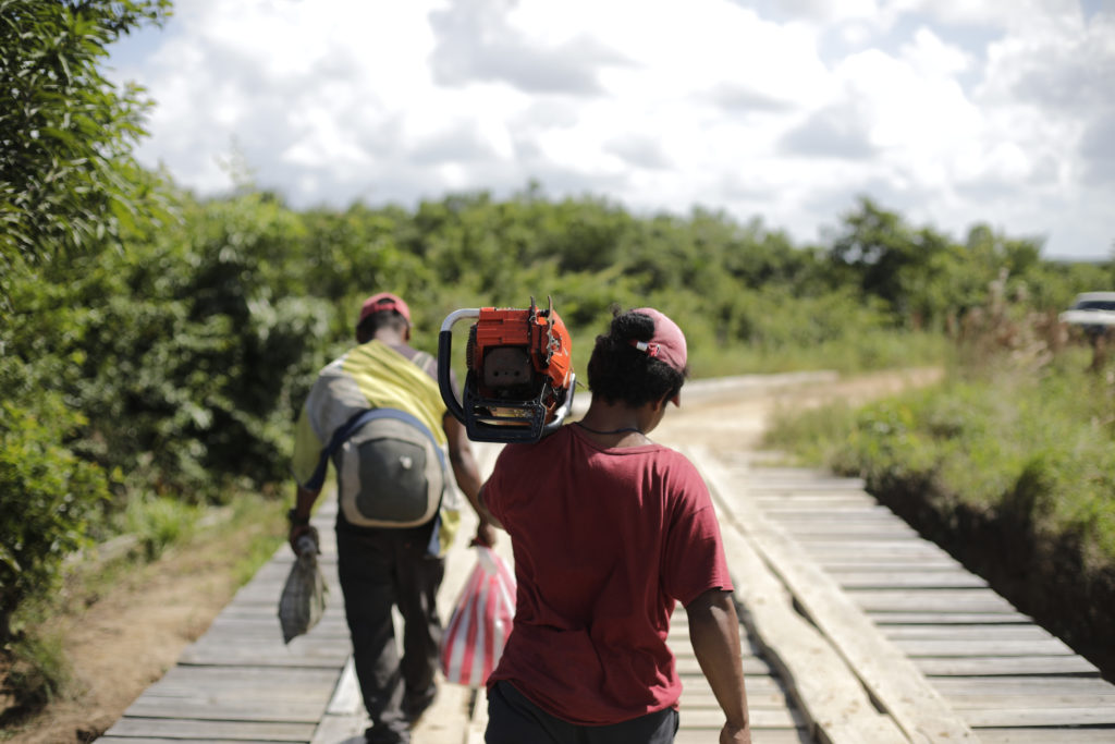 Sobre el río de Tapamlaya, en la comunidad de Tipi, hombres miskitos que trabajan en el negocio de la tala ilegal cargan motosierras y sacos. La Moskitia, 7 de diciembre de 2023. Foto: CC/Jorge Cabrera.