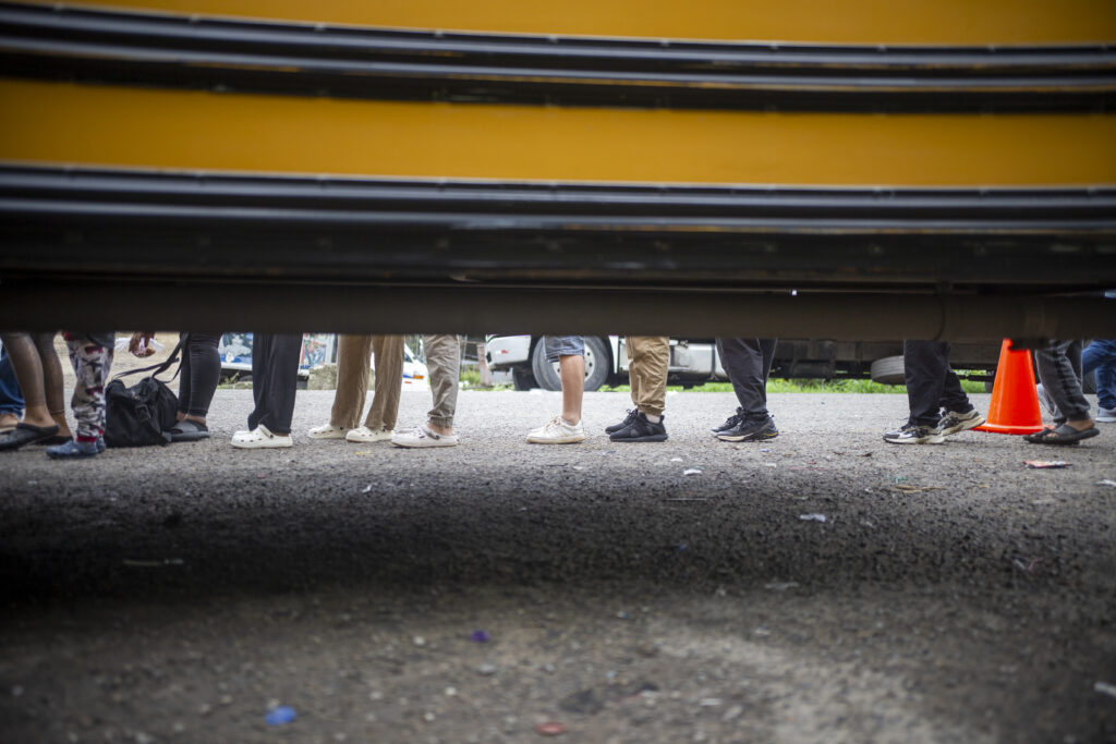 2023-08-24Trojes-MigrantesVenezolanos-Buses1 - Contra Corriente Un grupo de venezolanos con rumbo a Estados Unidos espera en fila para abordar un bus. Trojes, El Paraíso, 24 de agosto de 2023. Foto CC Fernando Destephen.