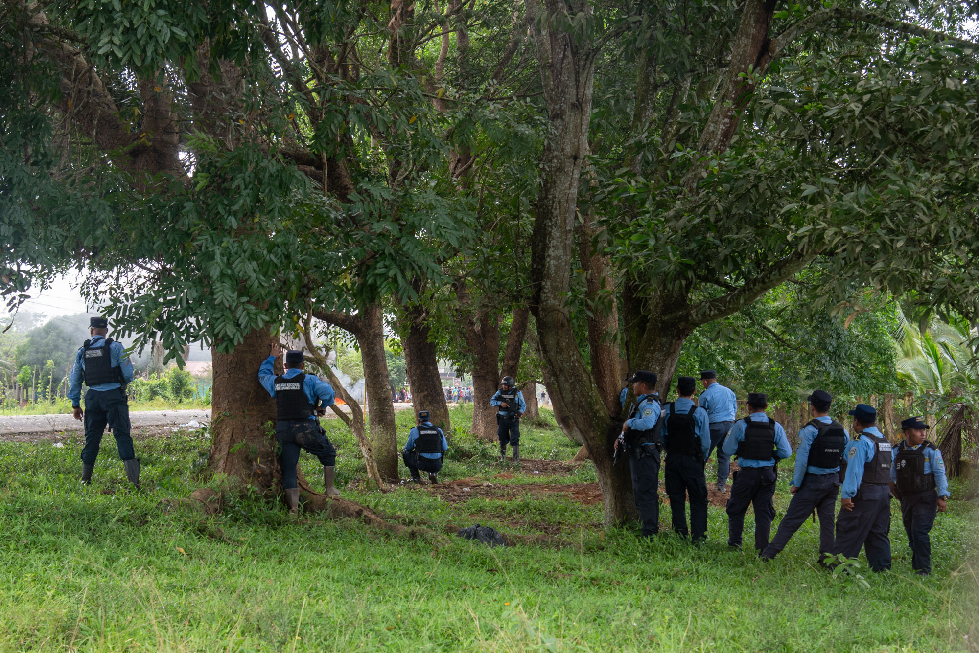 A la izquierda: policías y militares se retiran de la cooperativa La Chile, en enero de 2023, luego de un ataque armado contra campesinos de esa cooperativa. A la derecha: Agentes de la Policía Nacional de Honduras observan, sin intervenir, durante un ataque armado contra campesinos acorralados en la finca Tranvío, el 27 de enero de 2025. Fotos de Seth Berry.