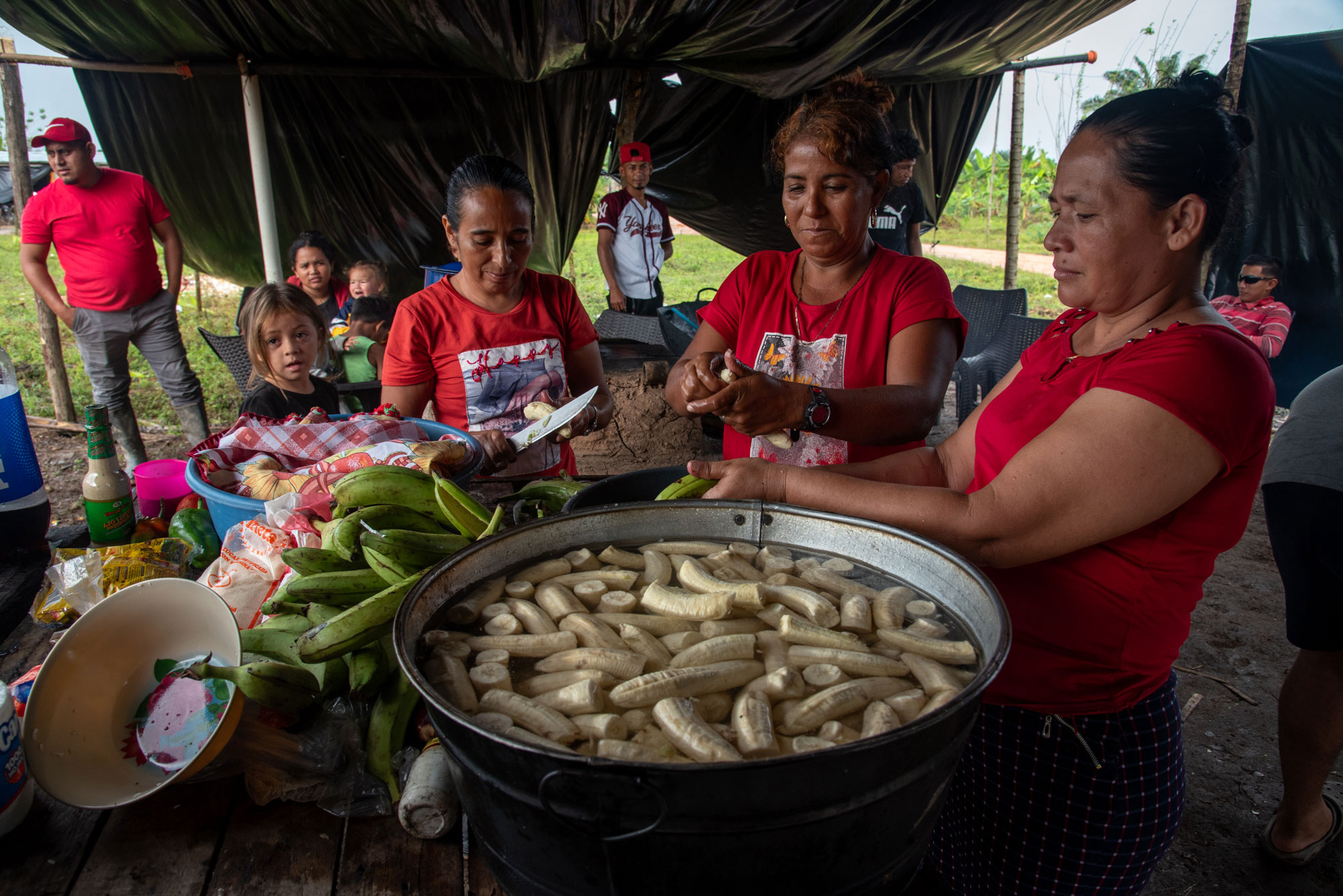 Campesinos de la finca Camarones preparan el almuerzo para los integrantes de la cooperativa días después de sufrir un desplazamiento forzado por parte de un grupo paramilitar, en diciembre de 2024. A la derecha, un joven se corta el pelo en la cooperativa La Chile.
